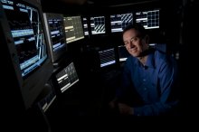 Photo of Prof. Matt Wilson sitting in front of multiple computer displays. 