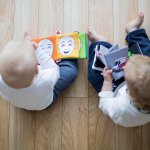 two infants sitting reading books